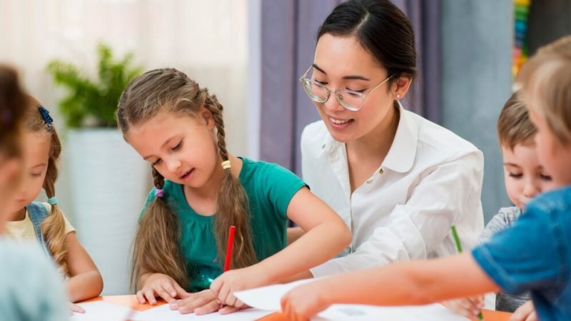 joven-profesora-ayudando-sus-alumnos-clase_23-2148633379 joven-profesora-ayudando-sus-alumnos-clase_23-2148633379