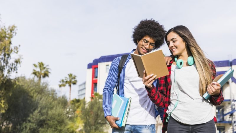 panoramic-view-diverse-teenage-couple-reading-book-outside-campus Formas de Titulación