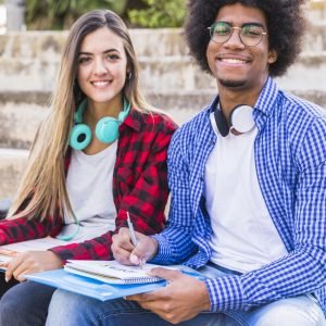 portrait-smiling-afro-male-student-sitting-with-her-girlfriend-outdoors-with-books Realiza tus Prácticas